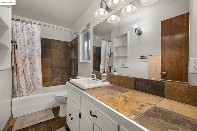 a bathroom with a granite countertop sink a toilet and shower