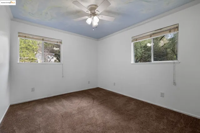 en empty room with windows and ceiling fan
