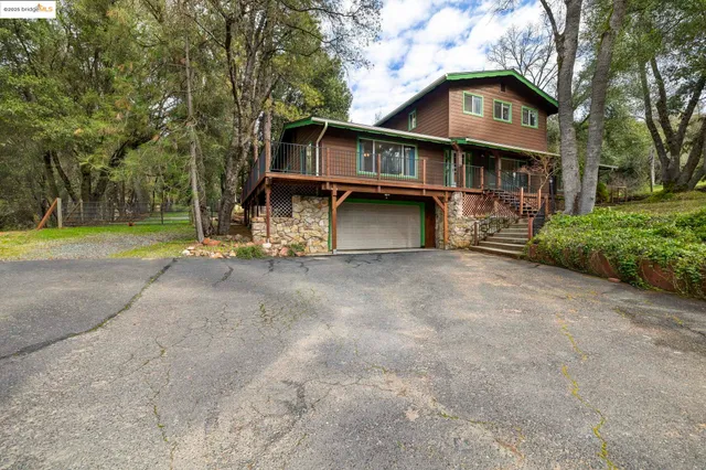 a view of a house with a yard and large trees