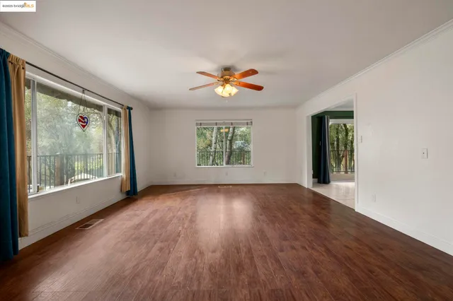 a view of an empty room with a window and wooden floor