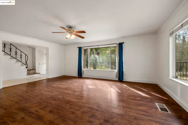 a view of an empty room with a window and wooden floor