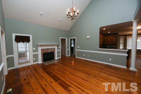 1008 Fieldgrass Place Raleigh, NC 27603 - Photo 2 of 13 a view of a livingroom with a fireplace a chandelier and wooden floor