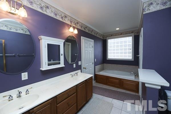 1008 Fieldgrass Place Raleigh, NC 27603 - Photo 7 of 13 a spacious bathroom with a bathtub sink and mirror