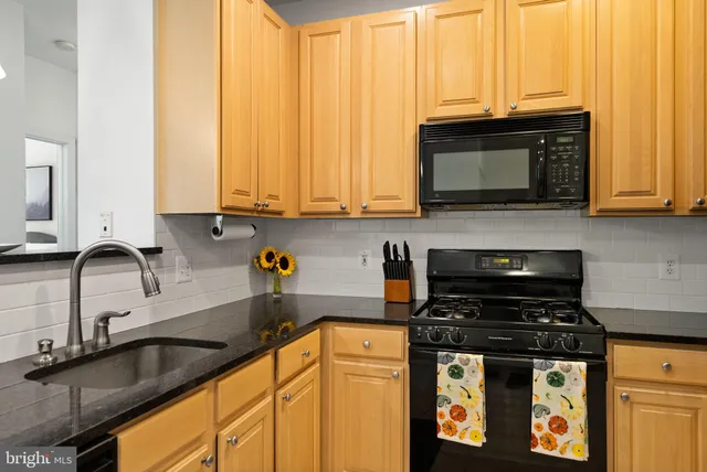a kitchen with stainless steel appliances granite countertop a refrigerator and a couch