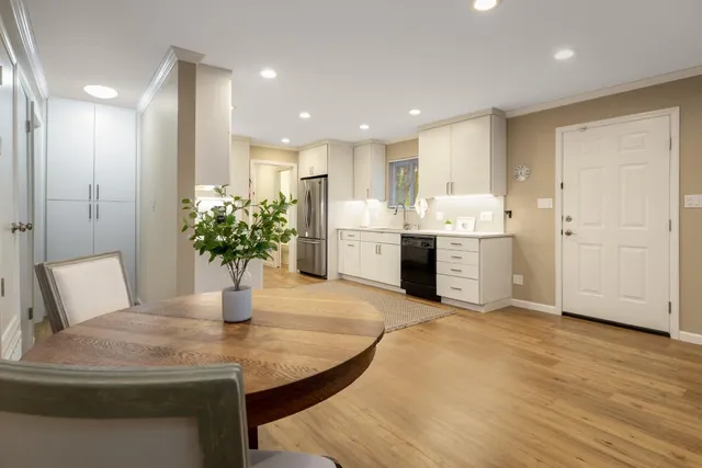 a room with stainless steel appliances kitchen island granite countertop a table and chairs