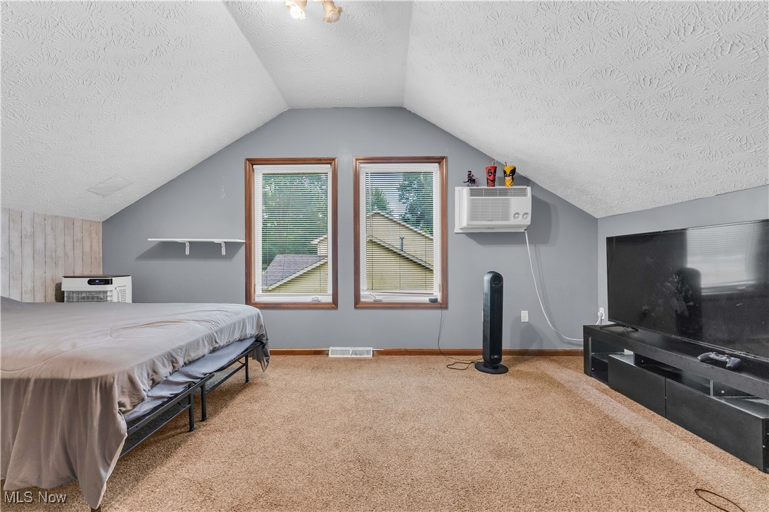 6834 Glendale Road North Ridgeville, OH 44039 - Photo 28 of 37 Carpeted bedroom with a textured ceiling, vaulted ceiling, and a wall mounted AC