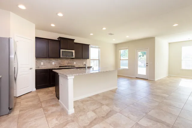 a large white kitchen with kitchen island a stove a refrigerator a sink and a oven