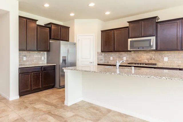 a view of kitchen with stainless steel appliances granite countertop a refrigerator and a sink