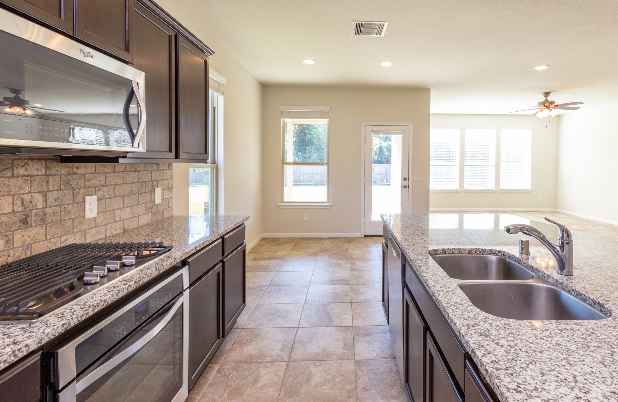 10 Log House Court Tomball, TX 77375 - Photo 20 of 50 a kitchen with kitchen island granite countertop a sink and a stove