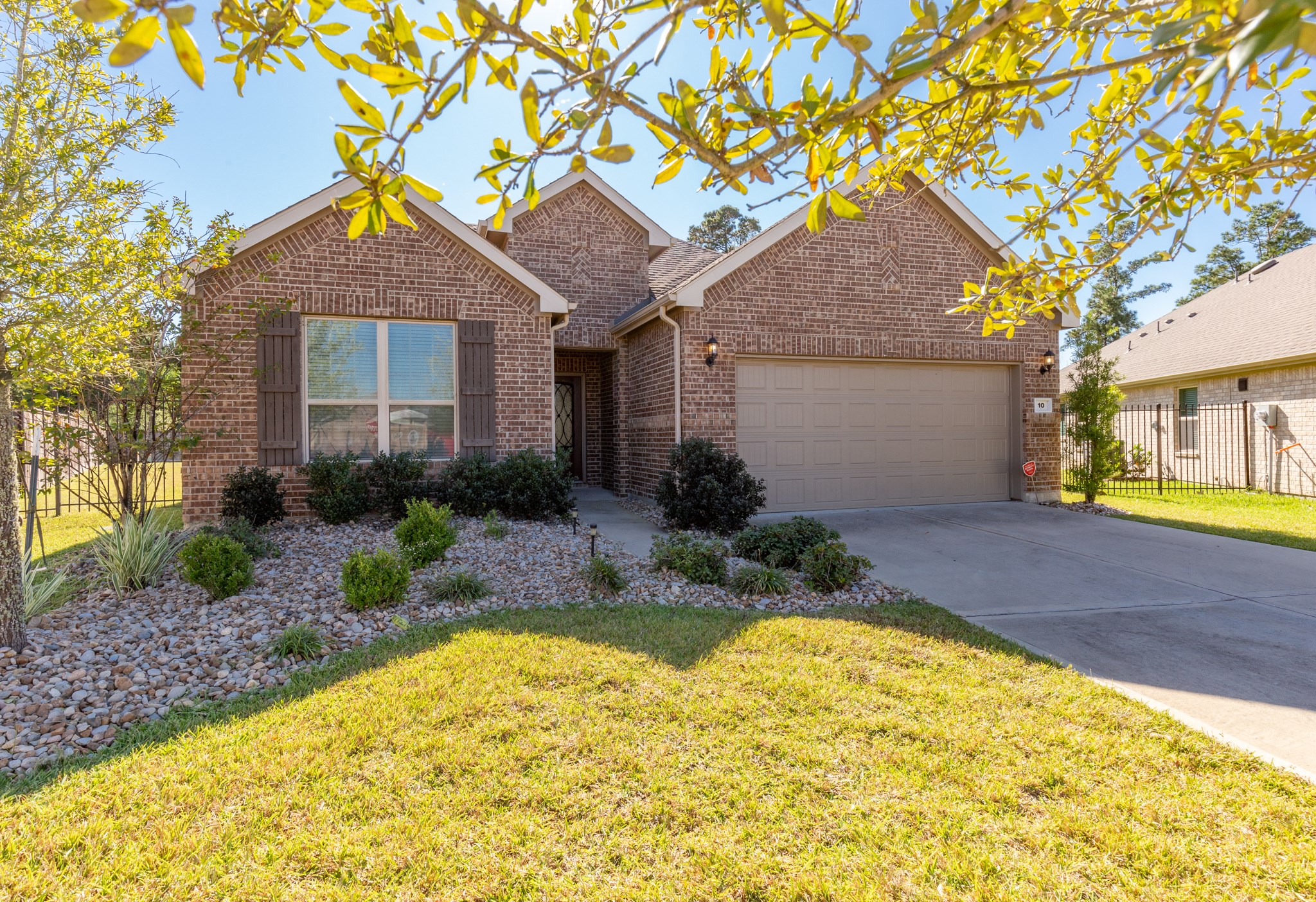 10 Log House Court Tomball, TX 77375 - Photo 2 of 50 This charming brick home features a well-maintained front yard with landscaped garden beds and a two-car garage. The driveway and walkway add to the inviting curb appeal, perfect for a welcoming entrance.