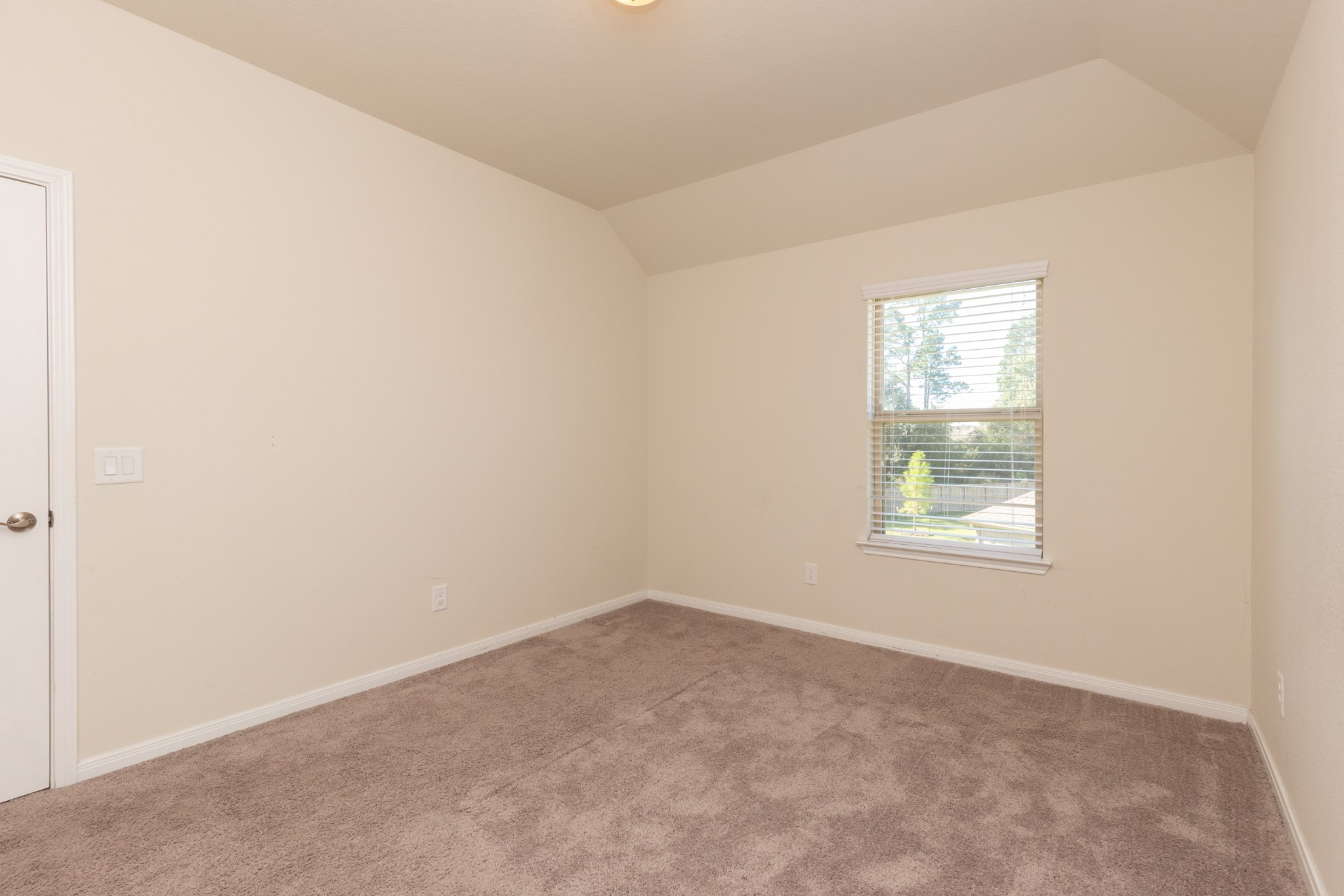 10 Log House Court Tomball, TX 77375 - Photo 36 of 50 This room features neutral walls, a single window with blinds allowing natural light, and a carpeted floor, making it a cozy and versatile space.