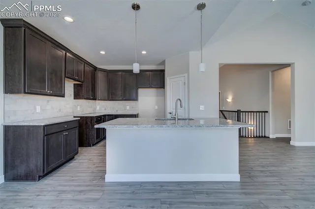 a large kitchen with stainless steel appliances granite countertop a sink a stove and a wooden floors