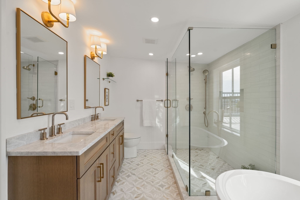 32 High Street Boston, MA 02129 - Photo 25 of 38 a bathroom with a granite countertop sink a toilet a mirror and shower