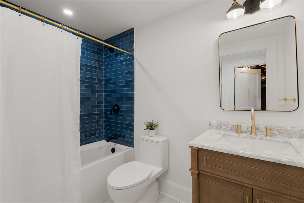 32 High Street Boston, MA 02129 - Photo 34 of 38 a bathroom with a granite countertop sink a toilet a mirror and shower