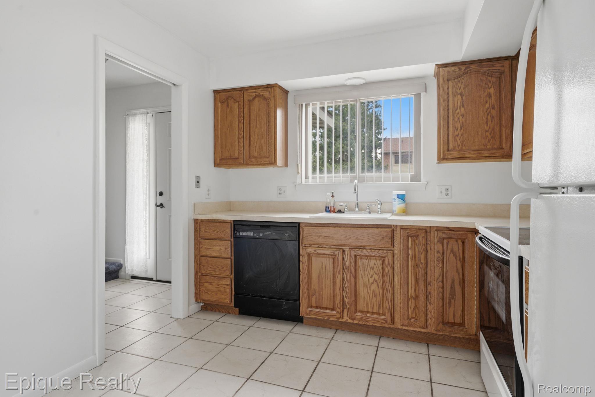 3895 Old Creek Road Troy, MI 48084 - Photo 11 of 23 Kitchen featuring white appliances, light countertops, wood finish cabinets, and light tile patterned floors