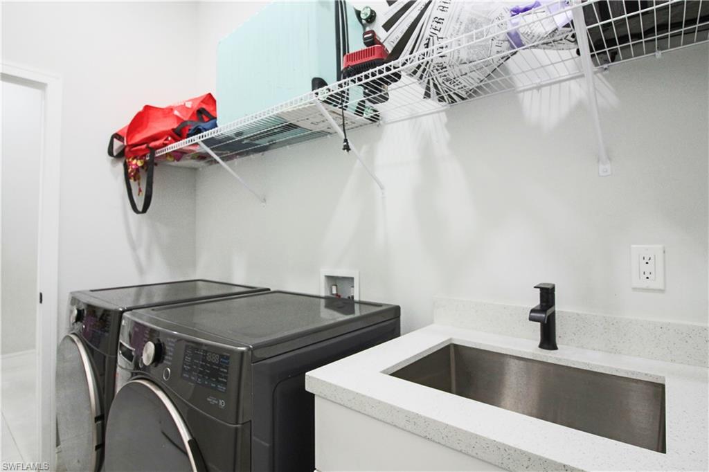 3902 4th Street Southwest Lehigh Acres, FL 33976 - Photo 15 of 34 Utility room with a built-in stainless steel sink, speckled countertop, and wall-mounted wire shelving