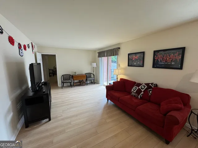 a living room with furniture kitchen view and a flat screen tv