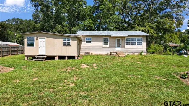 a front view of house with yard and trees in the background