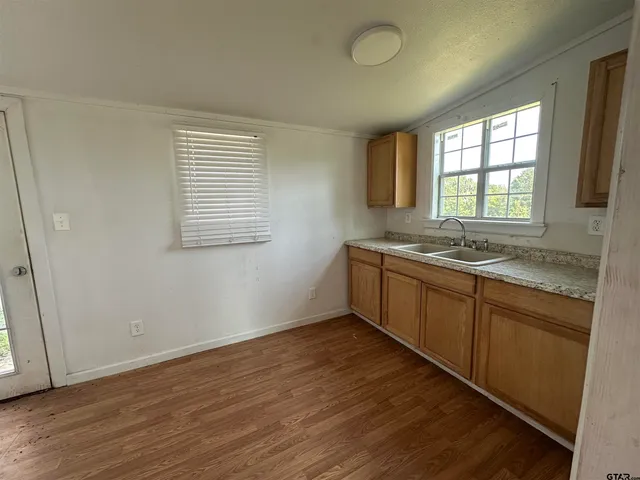 a view of a kitchen with wooden floor and a window