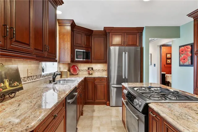 a kitchen with stainless steel appliances granite countertop a sink stove and refrigerator