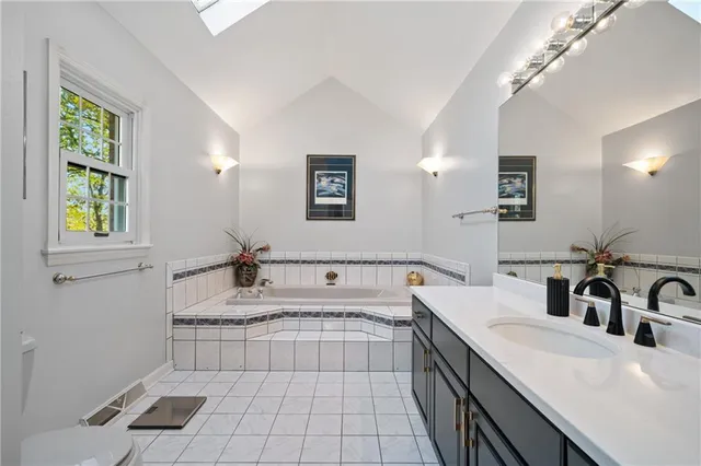 a spacious bathroom with a granite countertop sink a bathtub a mirror and vanity