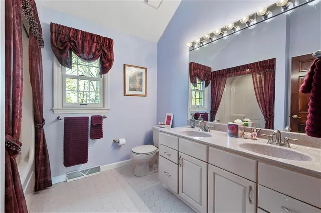a bathroom with a double vanity sink toilet mirror and window