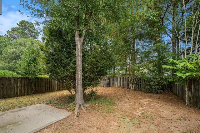 a view of a yard with plants and trees with wooden fence