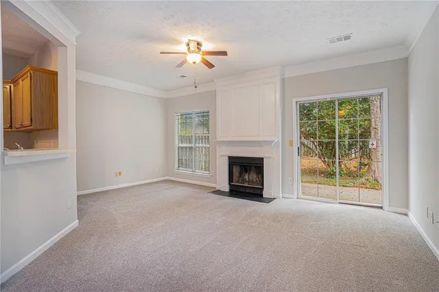 a view of an empty room with chandelier fan and fire place