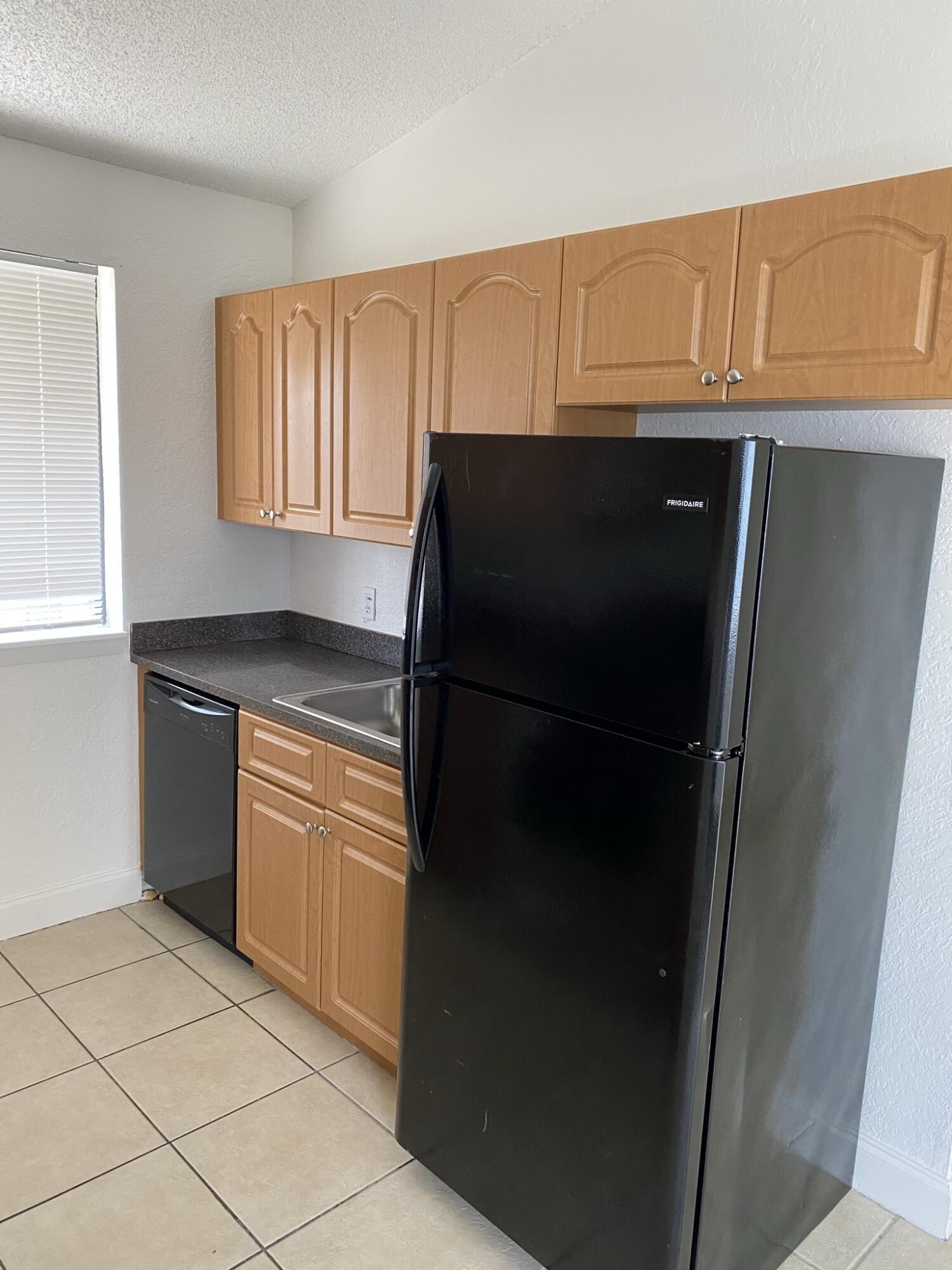 100 Nottingham Circle, Unit J Greenacres, FL 33463 - Photo 6 of 10 a kitchen with a refrigerator and cabinets
