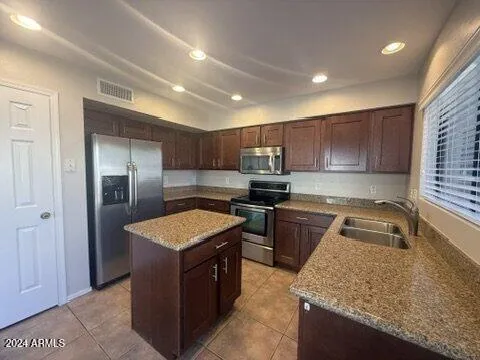 a kitchen with kitchen island granite countertop stainless steel appliances sink stove microwave and cabinets