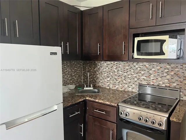 a kitchen with granite countertop a stove and a microwave