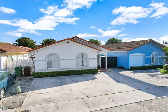 a view of house with wooden fence next to a yard