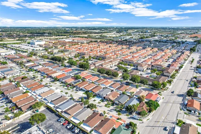 a front view of multi story residential apartment building with yard and parking