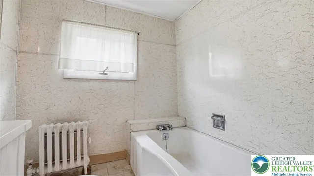 a view of a white house with a small yard and a large tree