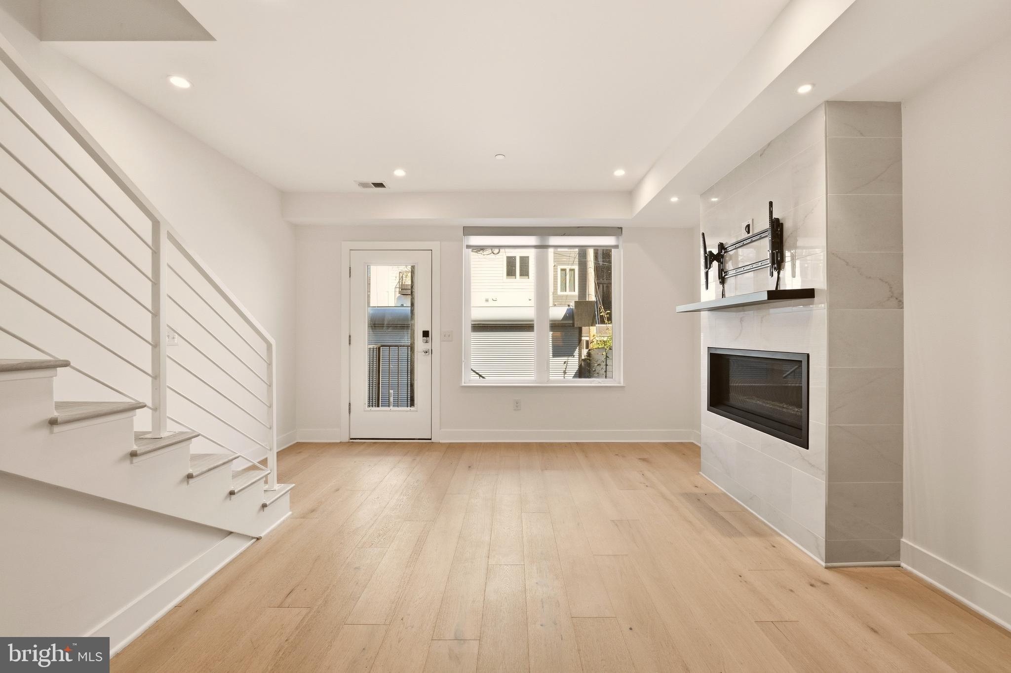 1023 16th Street Northeast, Unit B Washington, DC 20002 - Photo 10 of 25 a view of a livingroom with wooden floor and a kitchen space with an entryway