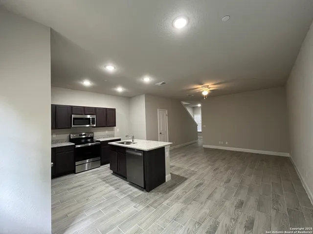 a kitchen with kitchen island granite countertop a sink and cabinets