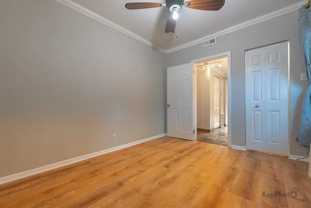 an empty room with a chandelier fan and wooden floor