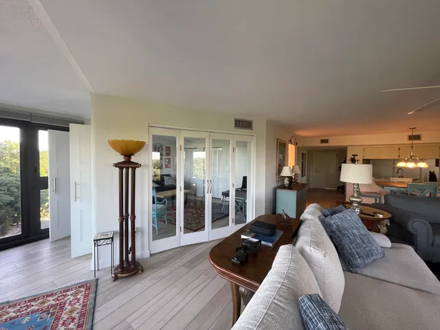 a living room with furniture large windows and wooden floor
