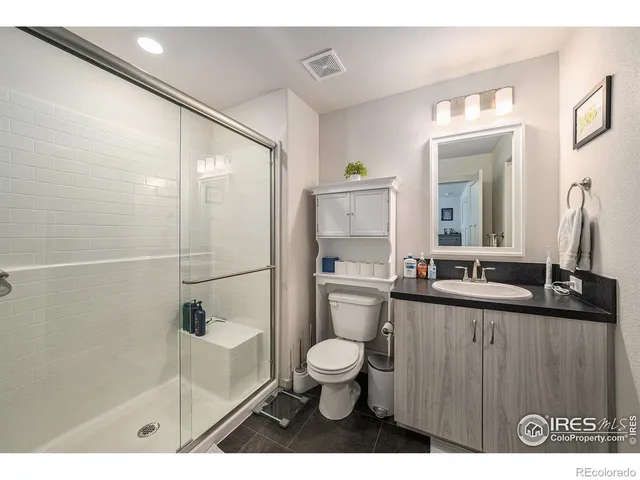 a bathroom with a granite countertop sink a toilet a mirror and shower