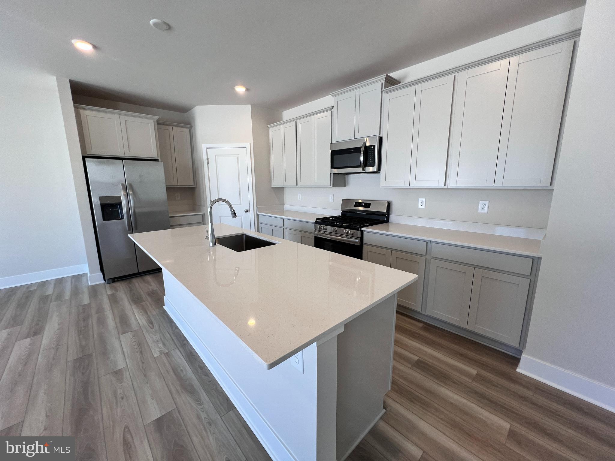 24718 Ridgeville Way Millsboro, DE 19966 - Photo 2 of 16 a kitchen with white cabinets sink and stainless steel appliances