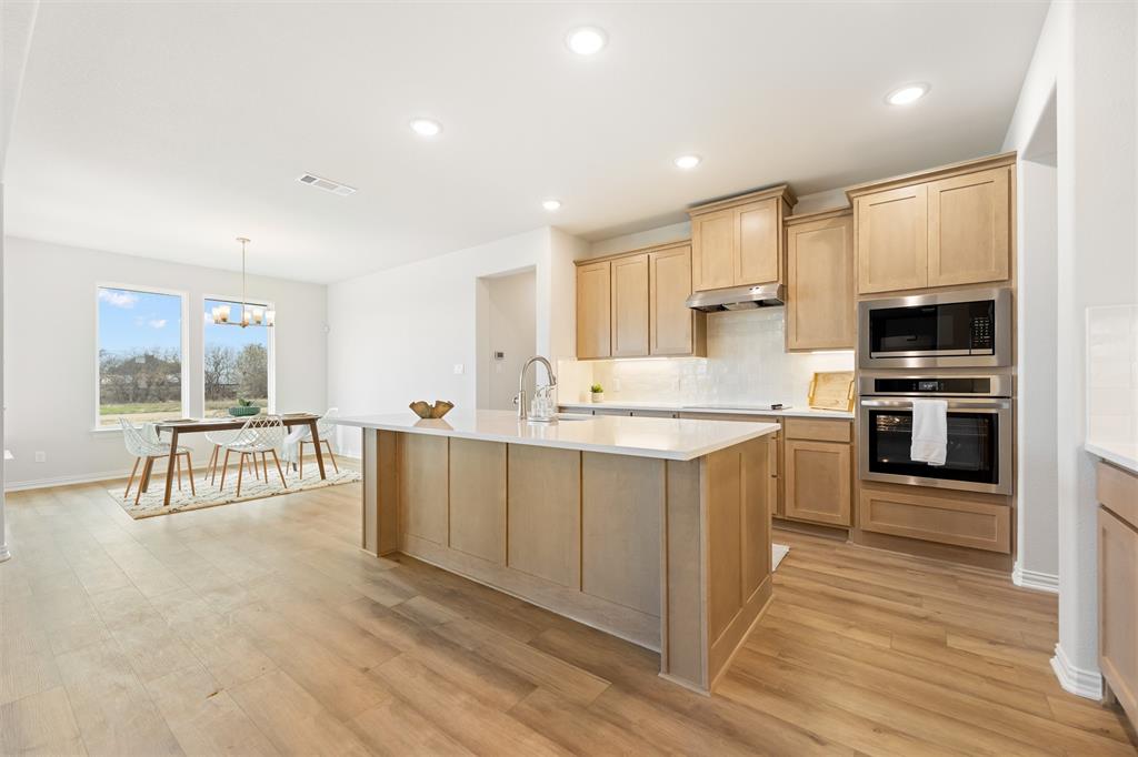 157 Brandywine Trail Rhome, TX 76078 - Photo 14 of 33 Kitchen featuring light brown cabinetry, appliances with stainless steel finishes, decorative light fixtures, a kitchen island with sink, and recessed lighting