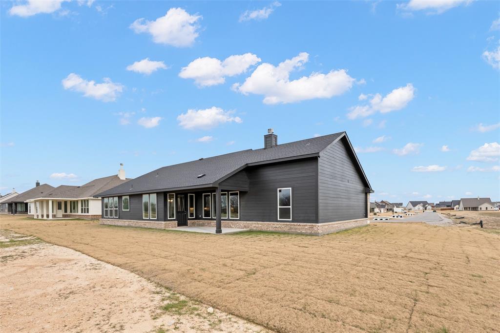 157 Brandywine Trail Rhome, TX 76078 - Photo 32 of 33 Rear view of house with a chimney, a patio, and a lawn