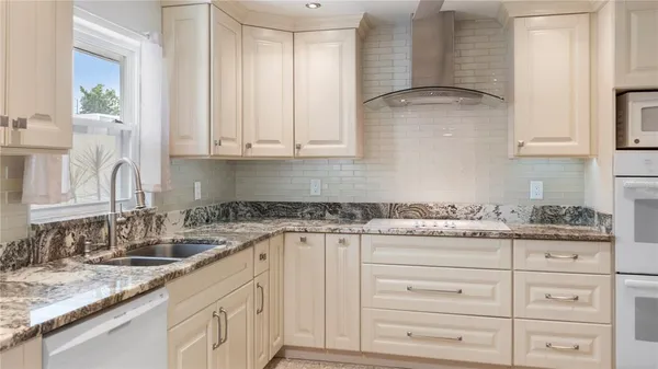 a kitchen with granite countertop white cabinets and white appliances