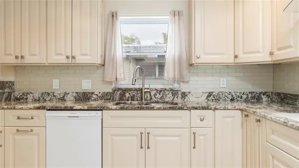 a kitchen with granite countertop white cabinets and a sink