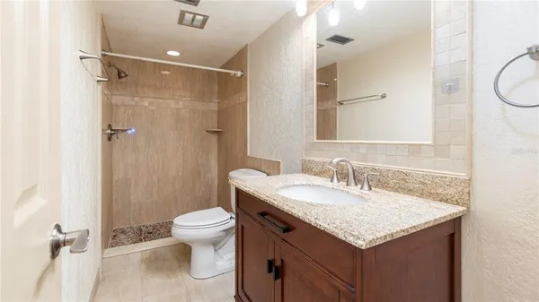 a bathroom with a granite countertop sink toilet and shower