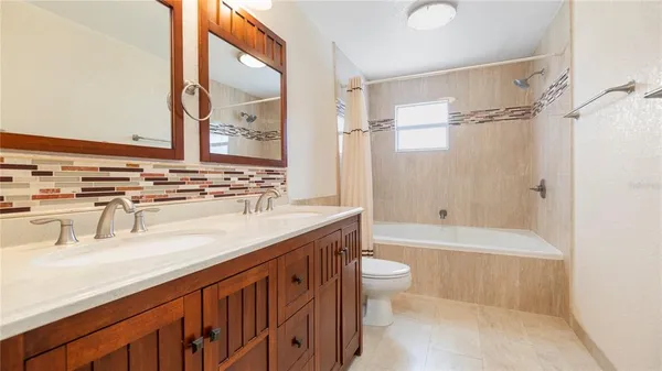 a bathroom with a granite countertop sink a toilet a mirror and bathtub