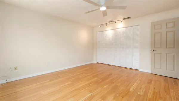 an empty room with wooden floor and fan