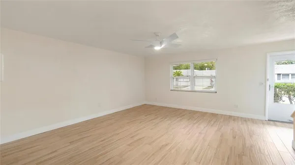 an empty room with wooden floor chandelier fan and windows