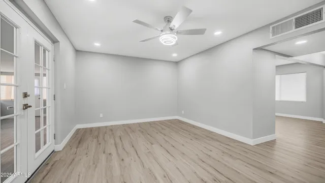 an empty room with wooden floor and windows