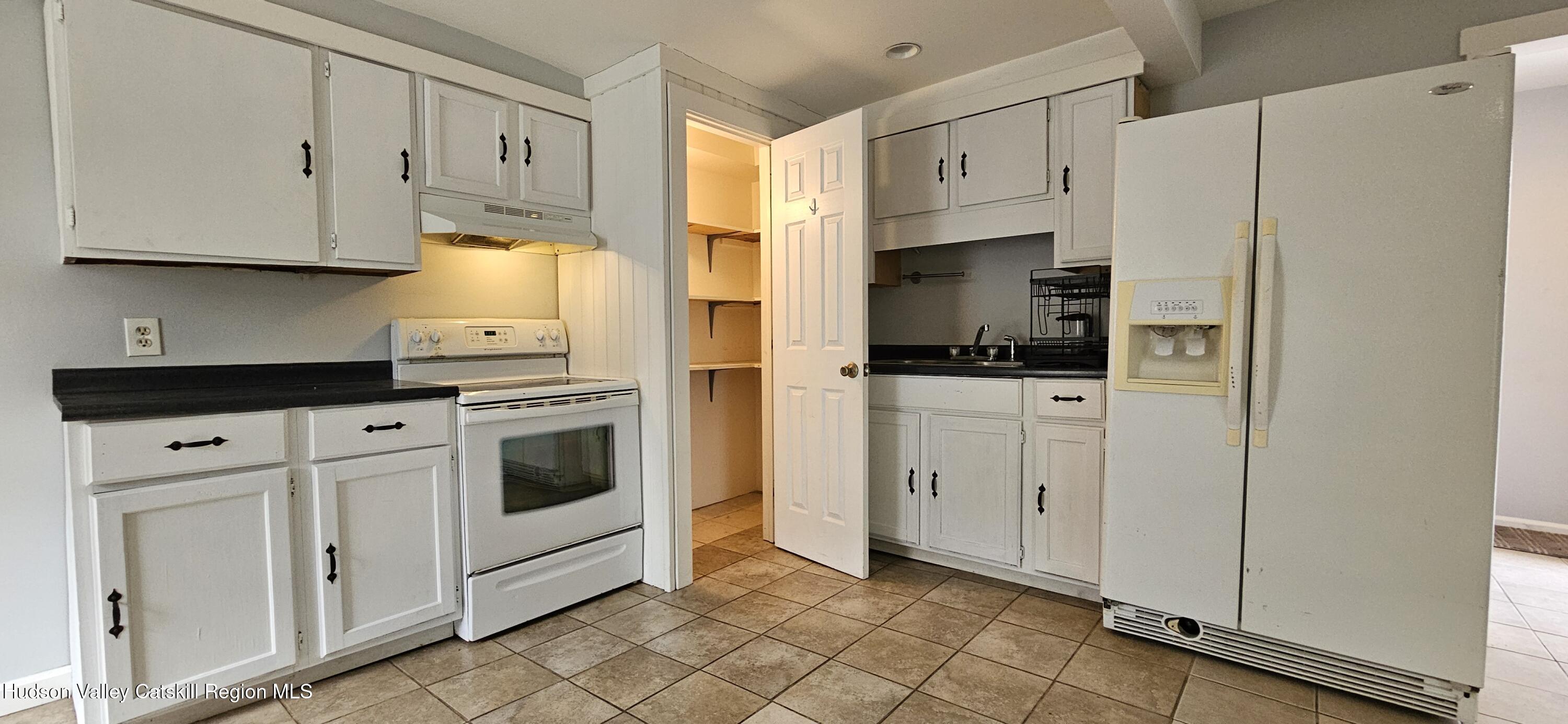 22 Spring Street Chatham, NY 12037 - Photo 22 of 61 a kitchen with white cabinets and white appliances